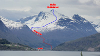 Západná strana masívu Skala (oblasť Stryn) s vrcholovou chatkou Skalatarnet (1843 m) a vyznačenou líniou zjazdu normálkou zo SZ (S1, E1, do 35°, modrý ľahký, prevýšenie do Fosdalen 1100 m, bodkovane je vyznačený zostup napešo), fotené 17.5.2013 z cesty do Utvik